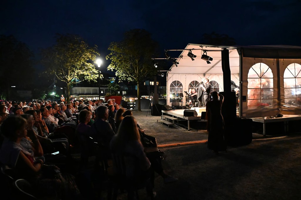 Stimmungsvoller Abendblick auf das beleuchtete Festzelt und das Publikum