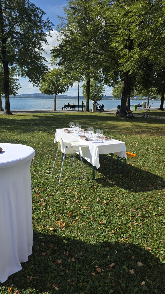 Gedeckte Tafeln im Schatten der Bäume direkt am See